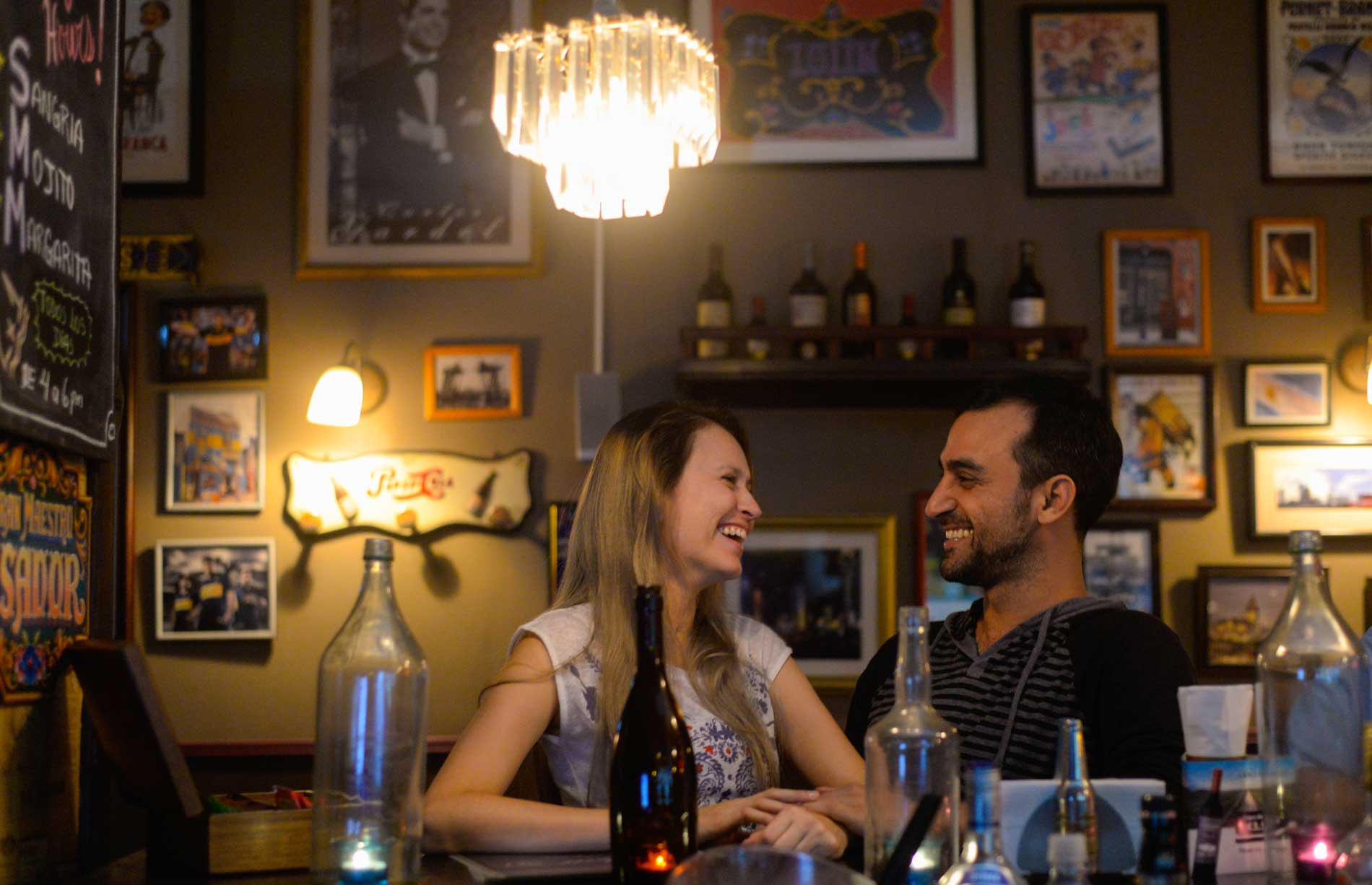 Una pareja comparte una mesa entre las luces cálidas y los recuerdos de Aquí Es