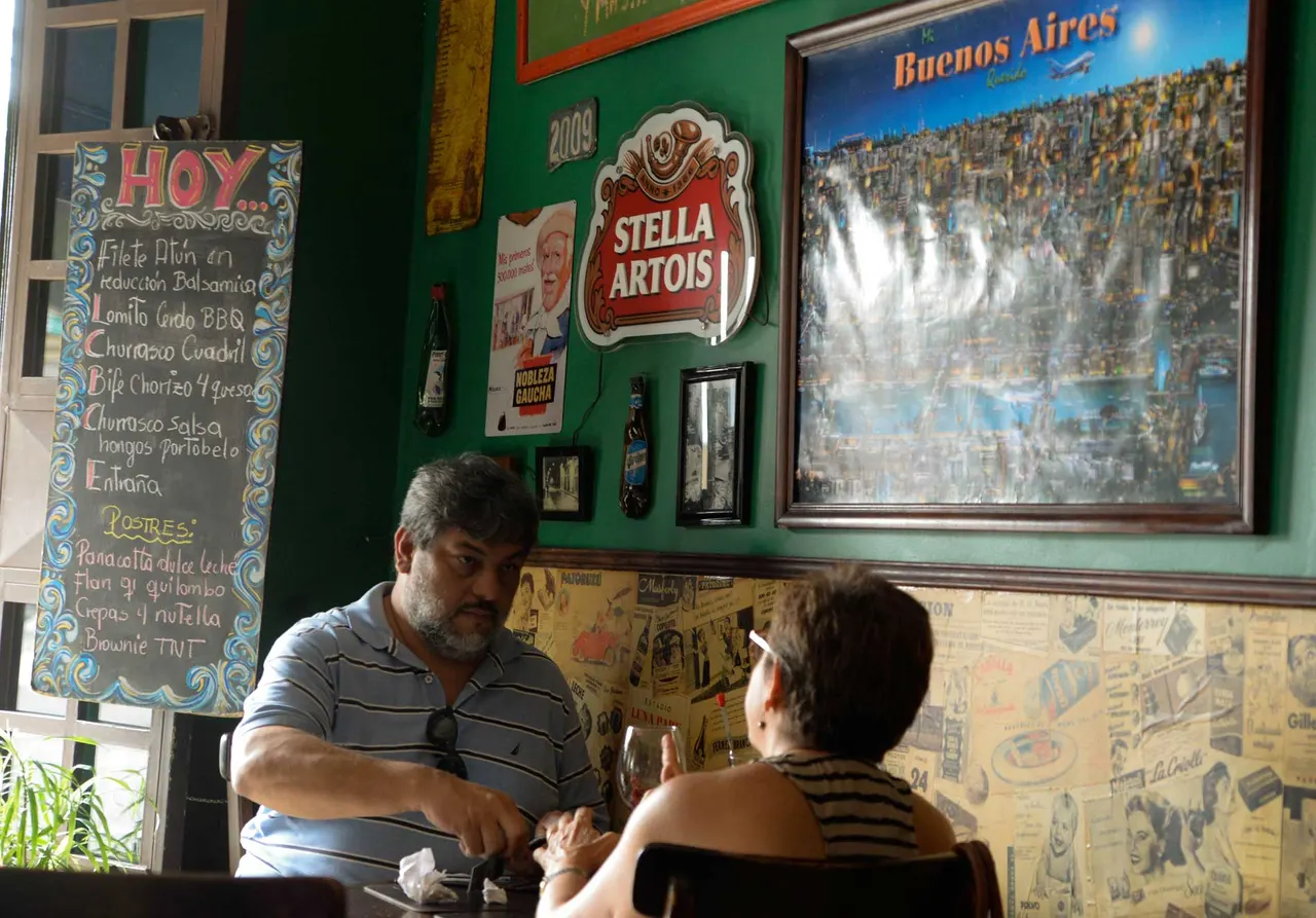 Comensales en una mesa junto a la pared de recuerdos