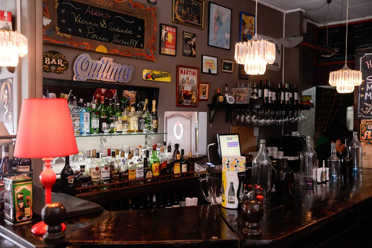 Vista del bar con botellas, copas y una lámpara roja