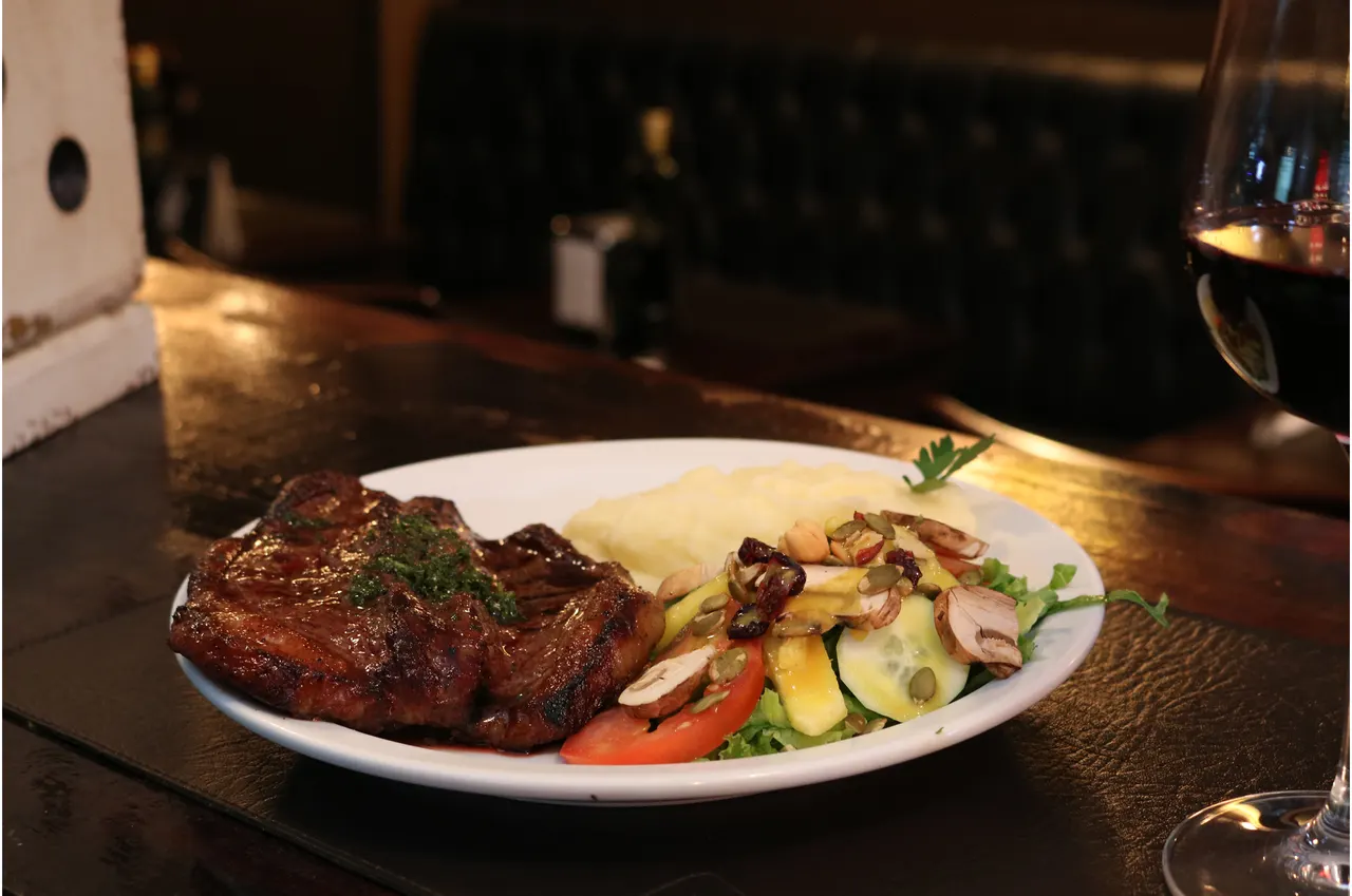 Carne a la parrilla con guarniciones y una copa de vino