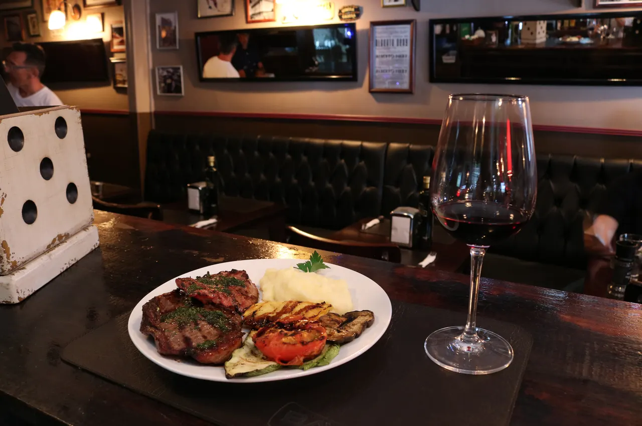 Plato de carne y guarniciones en una mesa con copas