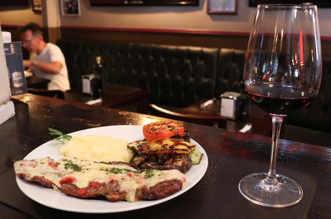 Plato de carne acompañado de guarniciones y vino