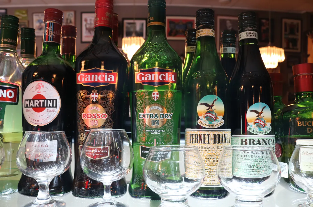 Botellas de bebidas y copas en el bar de Aquí Es