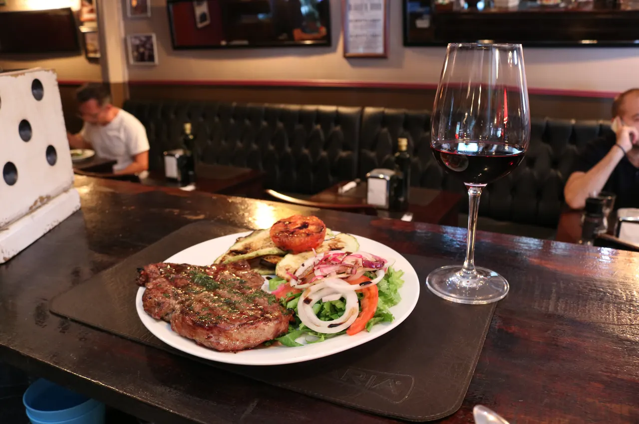 Plato de carne con guarniciones junto a una copa