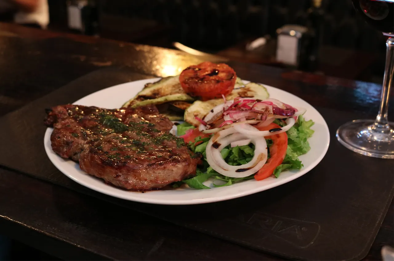 Corte a la parrilla servido con ensalada fresca en Aquí Es