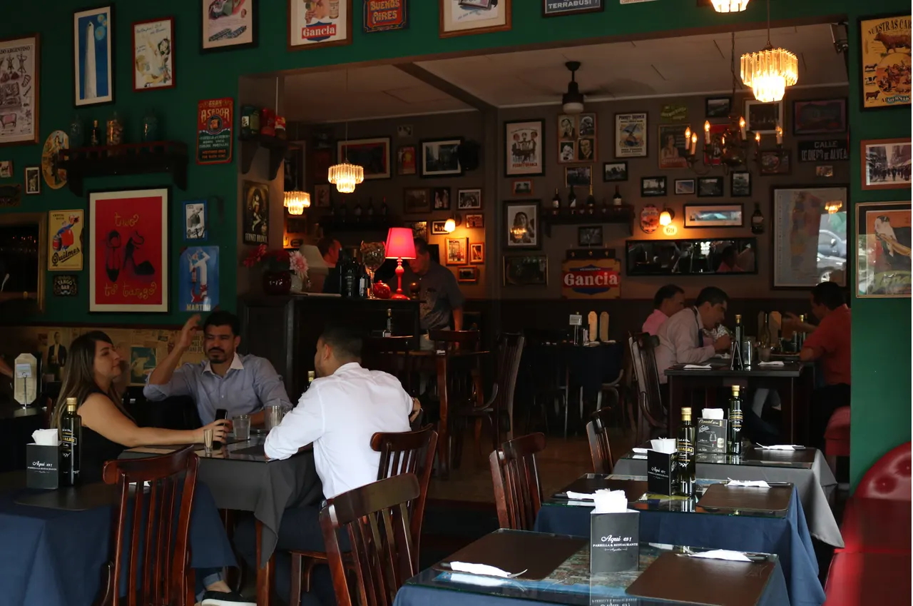 Mesas del restaurante con comensales y recuerdos argentinos
