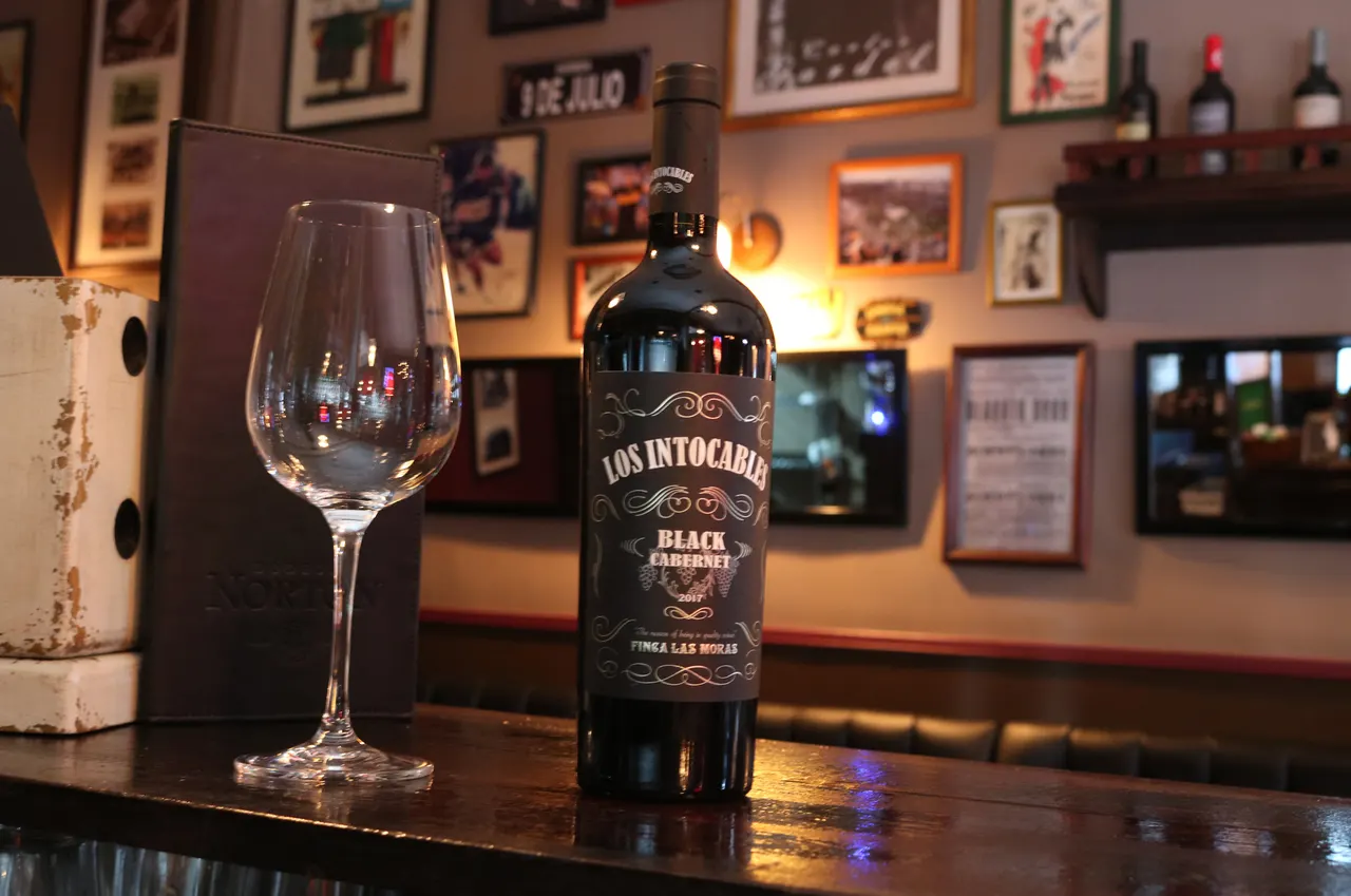 Botella de vino sobre la mesa frente a las fotografías del salón